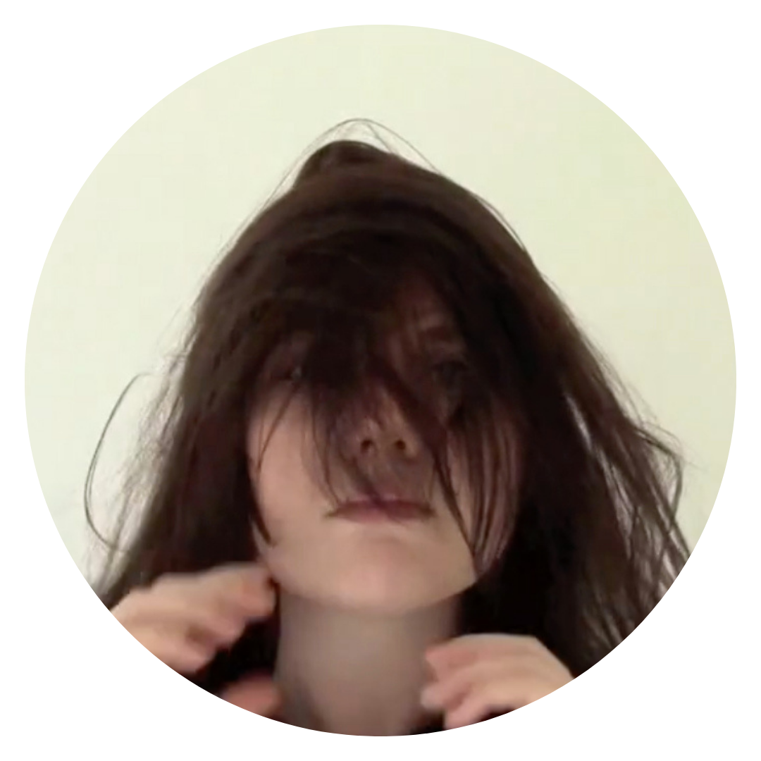A photograph of the artist, KP Culver, taken from one of their film works. In it they are running their hands repeatedly through their long dark hair, so their face is obscured.